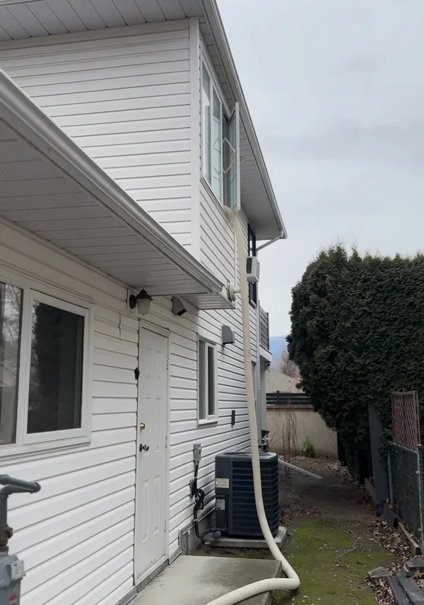Blown-in hose running from the truck along the side of a two storey house and in through an upstairs window.