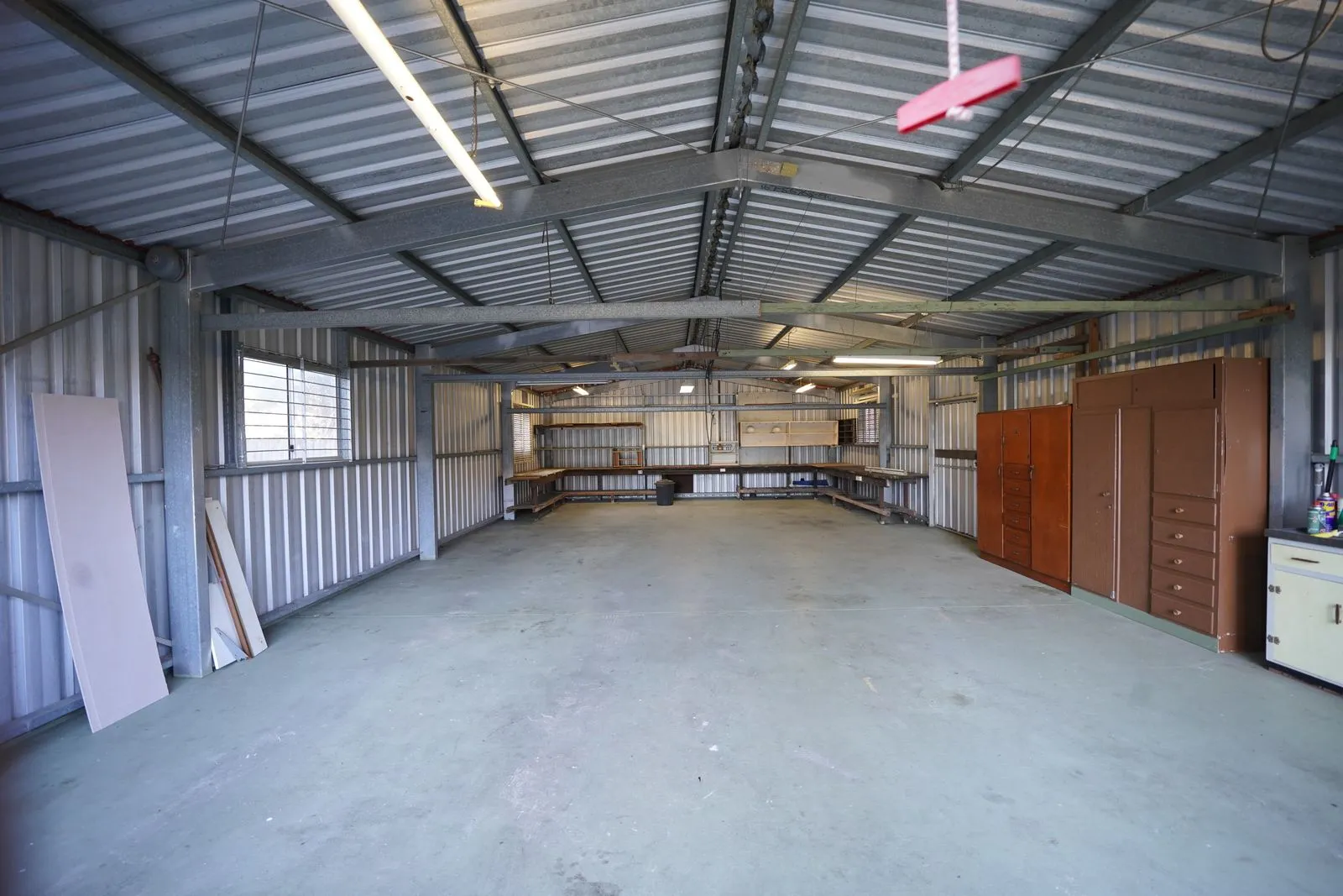 Empty metal building interior with steel walls and a bare concrete floor before insulation