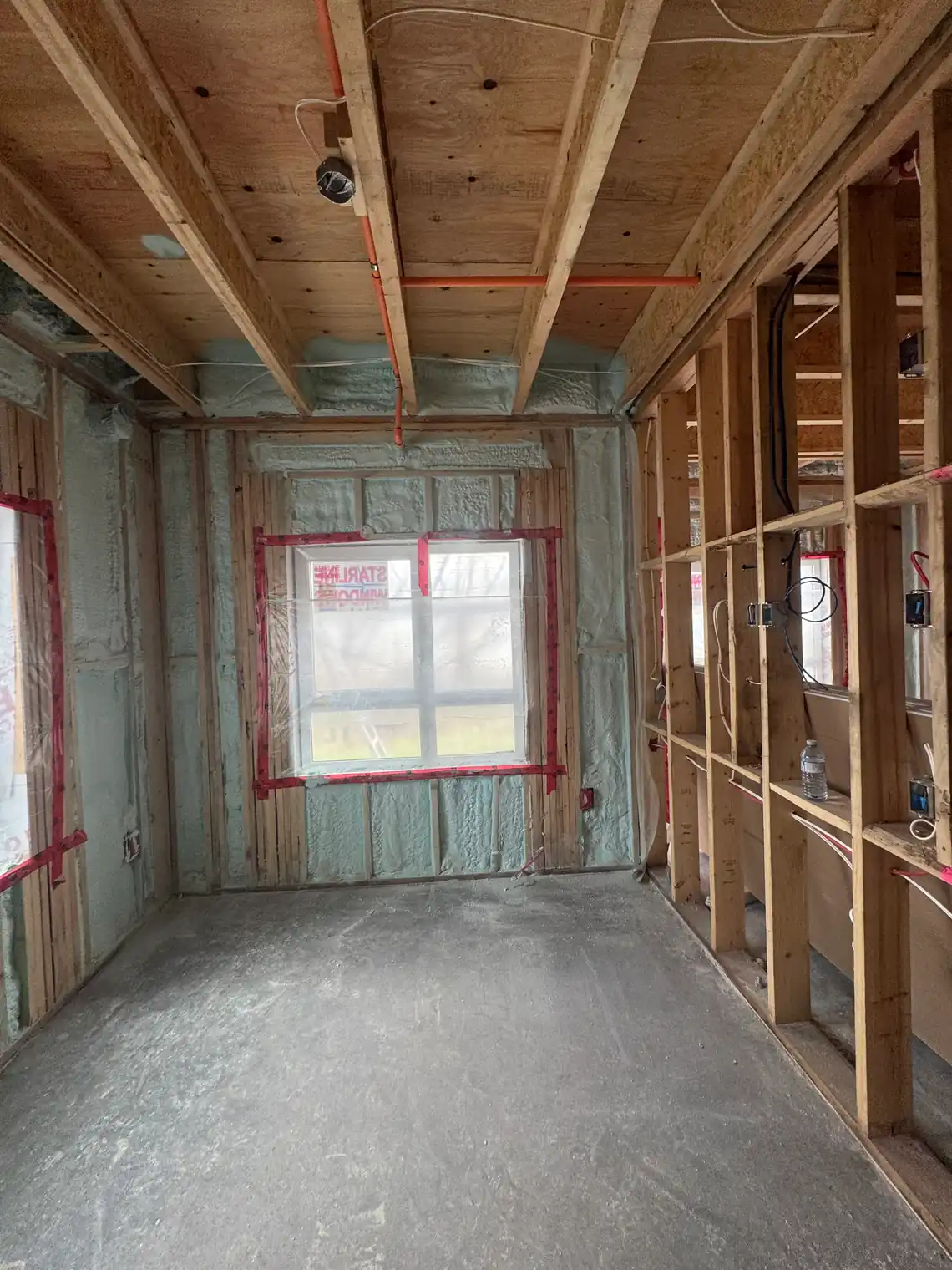 Closed-cell spray foam in the open stud bays and along the band above the floor of a BC new build